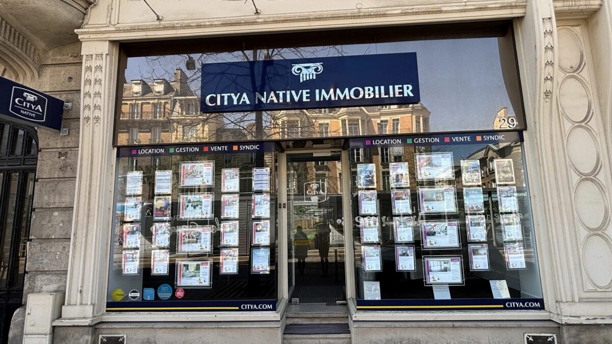 Façade d'une agence immobilière Citya Immobilier avec vitrine d'annonces de biens à vendre