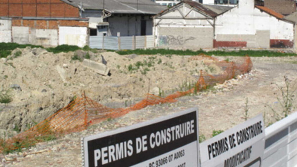 Panneau de permis de construire affiché devant une maison en construction